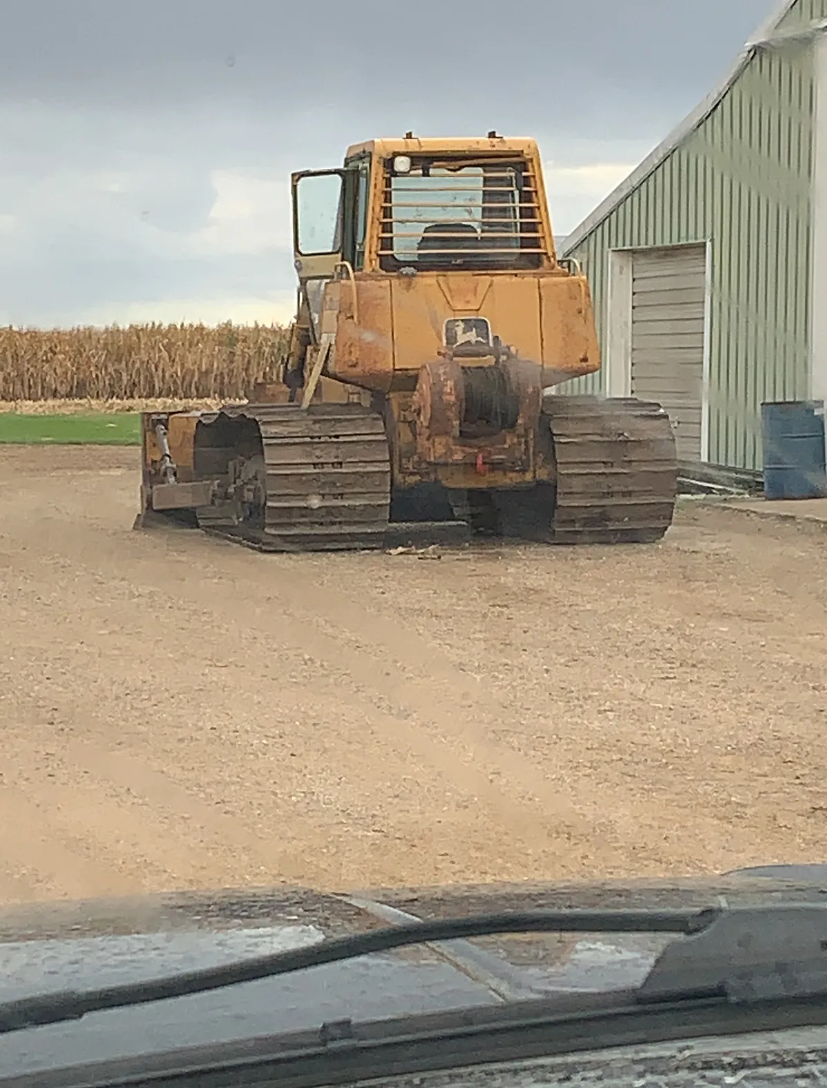 Salz Caterpillar dozer parked beside a white farm building