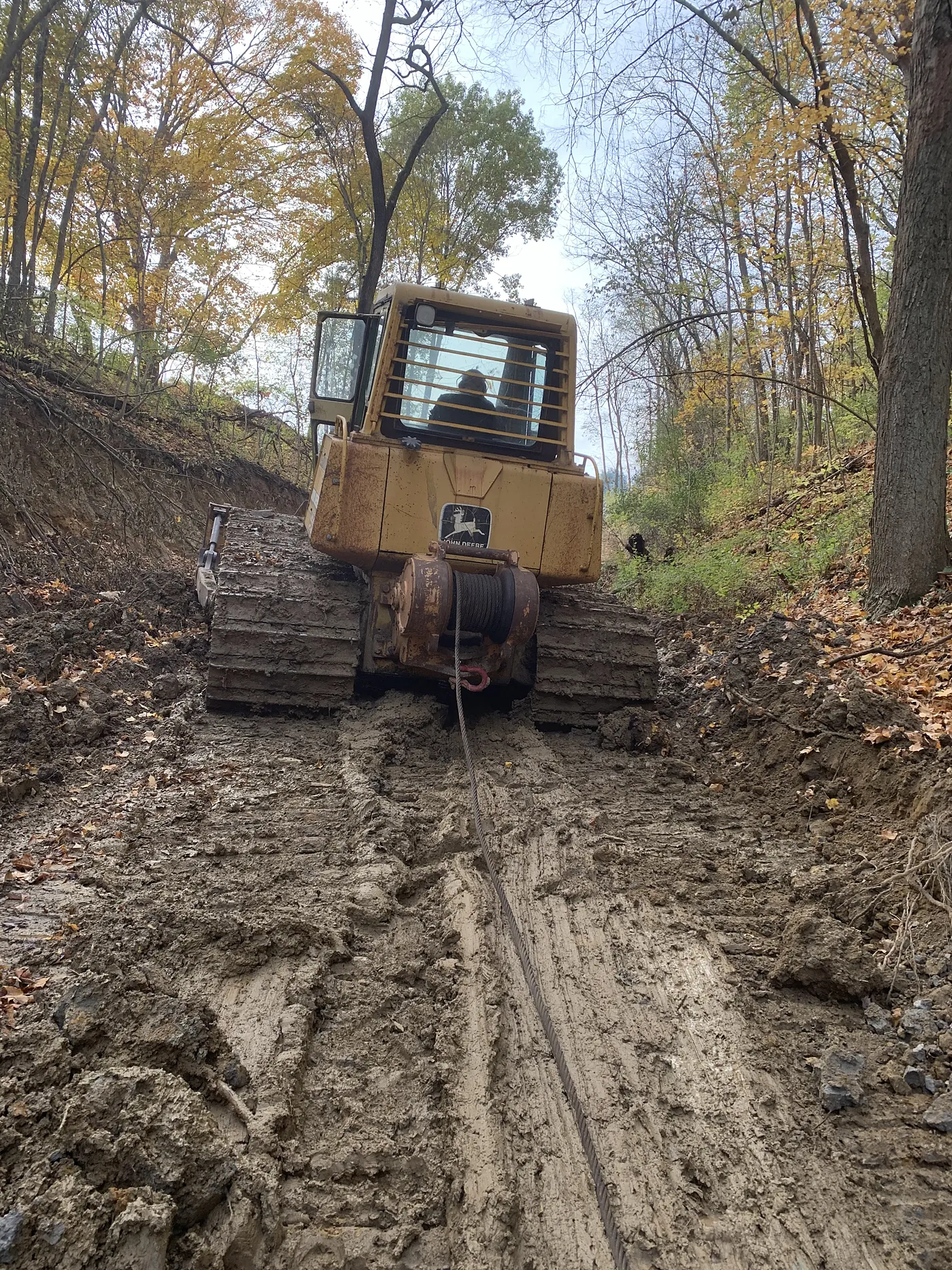 Dozer cutting an access lane through a wooded lot in autumn