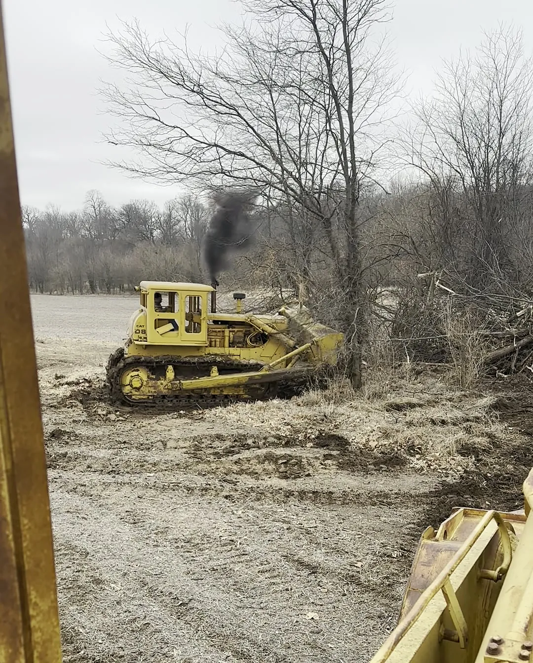 Yellow Salz dozer pushing brush and a downed tree along a fence line